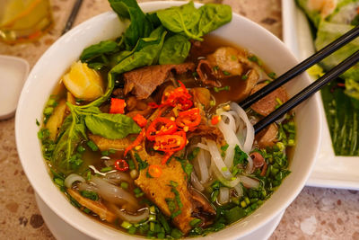 Pho bo or vietnamese soup with beef and meat balls served in a white bowl at the restaurant. 