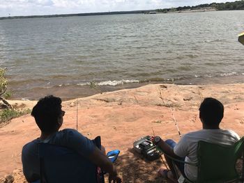 Rear view of people sitting on beach