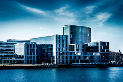 Buildings by river against sky