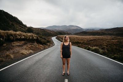 Young woman standing on road against mountain range