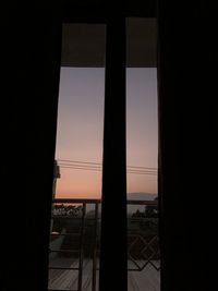 Silhouette buildings seen through window during sunset