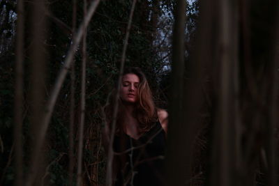 Young woman amidst plants in forest