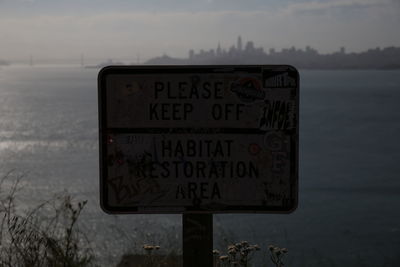 Information sign on beach against sky