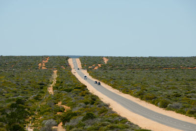 Road leading towards landscape against clear sky