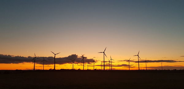 Silhouette of wind turbines on land during sunset