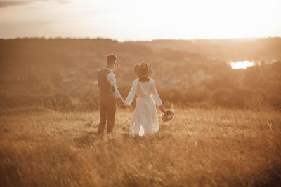 Couple kissing on field against sky