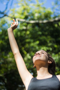 Girl with hand raised against tree