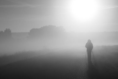 Rear view of silhouette man standing on landscape against sky