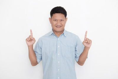 Portrait of young man standing against white background
