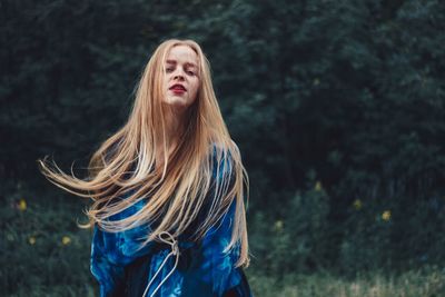 Young woman standing against trees in forest