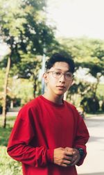 Portrait of young man standing against trees