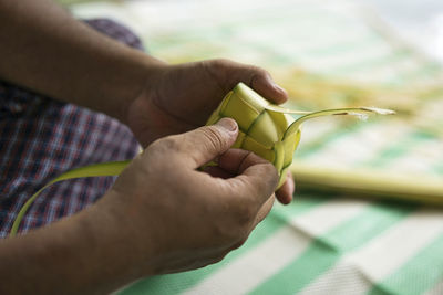 Weaving the coconut leaves making the ketupat, a traditional malay cuisine for the eid celebration