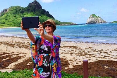 Portrait of young woman using mobile phone at beach