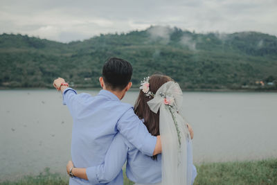 Rear view of couple standing against sky