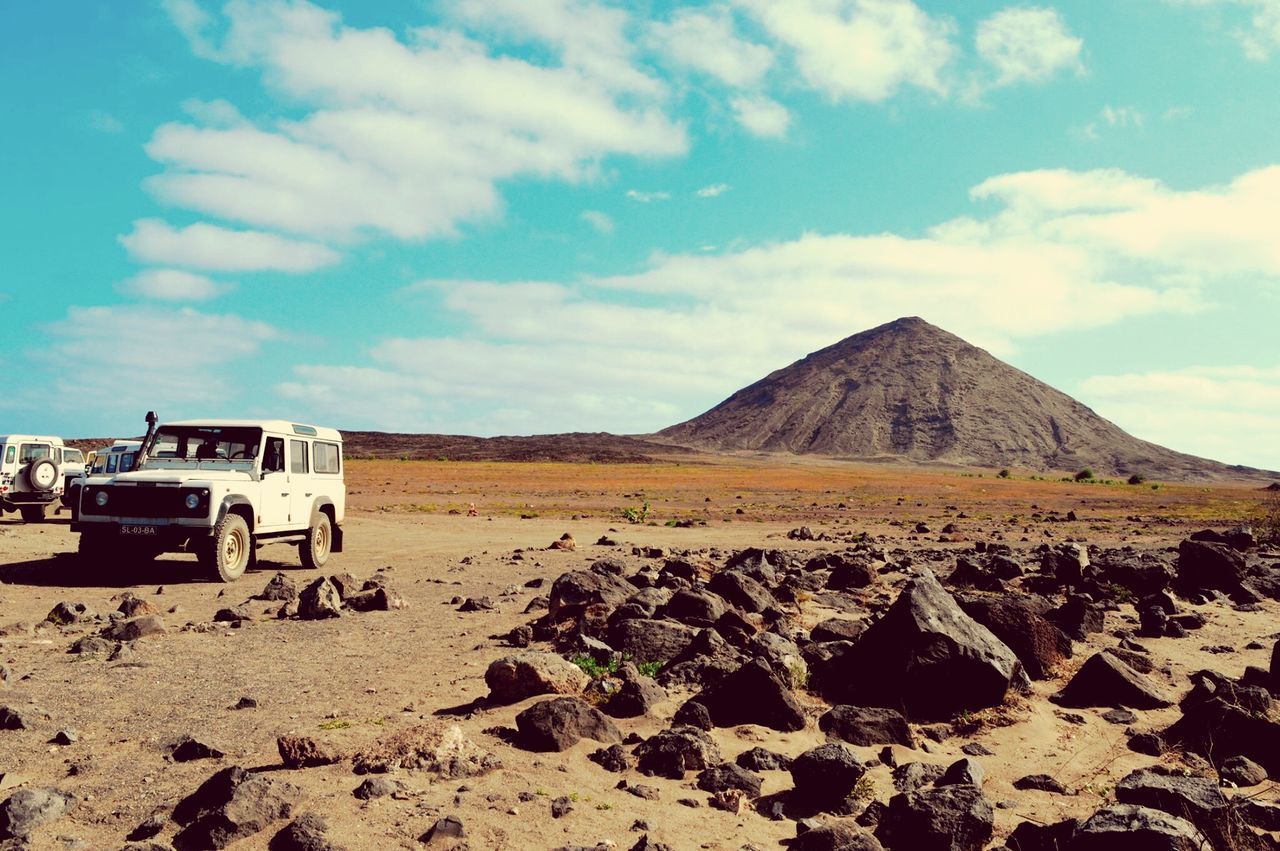 sky, mountain, landscape, transportation, cloud - sky, tranquility, sand, tranquil scene, cloud, scenics, mode of transport, desert, nature, car, land vehicle, travel, mountain range, arid climate, beauty in nature, day