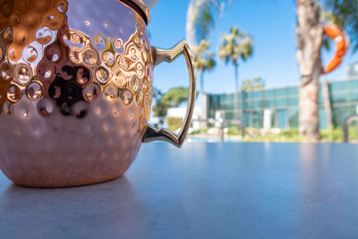 Fresh moscow mule cocktail with ice, lime and mint leaves in copper mug on swimming pool. 