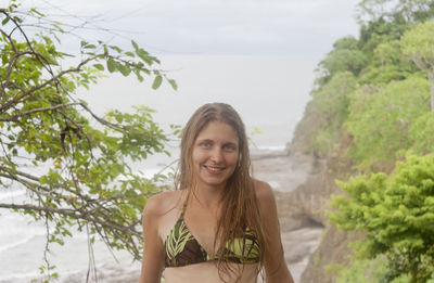 Portrait of happy mid adult woman standing against sea