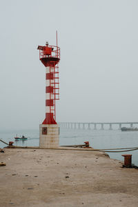 Lighthouse on beach against clear sky