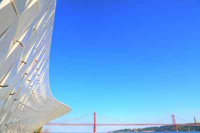 Low angle view of suspension bridge against blue sky