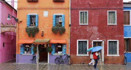 Woman walking on street against buildings in city