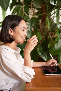 Side view of young woman using mobile phone