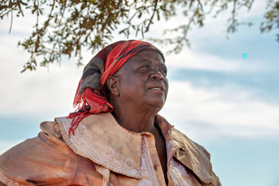 Low angle view of woman looking away against sky