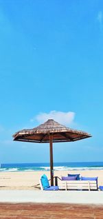 Thached sun shade on beach against clear blue sky