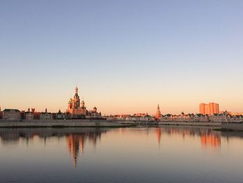 Reflection of buildings in lake against clear sky