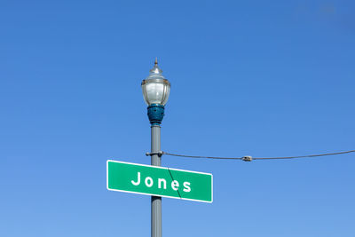 Low angle view of road sign against clear blue sky