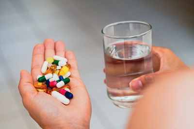 Cropped hand of woman holding pills against black background