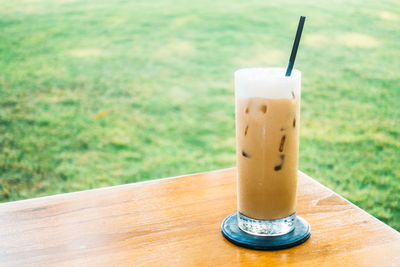 Close-up of cold coffee in glass on table against grass