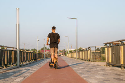 European man is riding on scooter with his small dog. walking with dog on empty street of city. 