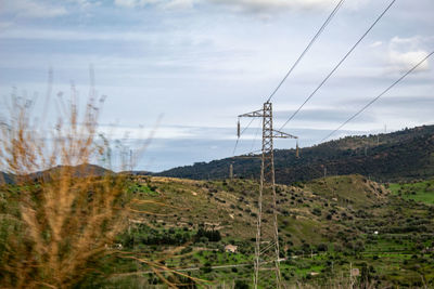 Electricity pylon on land against sky