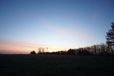 Silhouette trees on field against sky during sunset