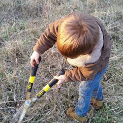 Boy cutting plants on field