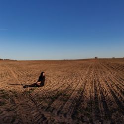 Woman relaxing of field against clear sky