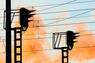 Low angle view of silhouette electricity pylon against sky