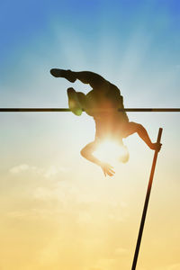 Low angle view of man jumping against sky