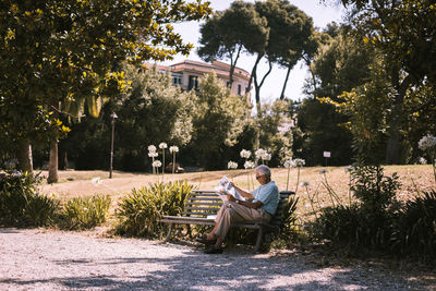 Man sitting on seat against trees