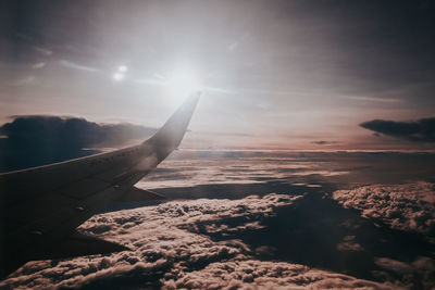 Airplane wing against sky during sunset