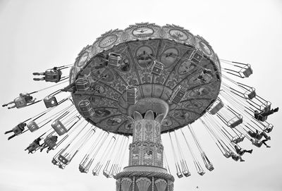 Low angle view of chain swing ride against sky