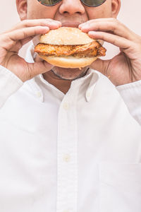 Midsection of man eating burger