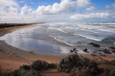 Scenic view of beach against cloudy sky