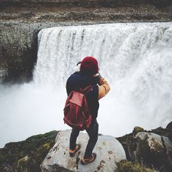 Rear view of man photographing waterfall