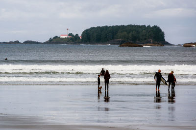 People at beach against sky