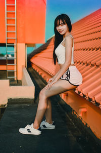 Full length portrait of young woman sitting outdoors