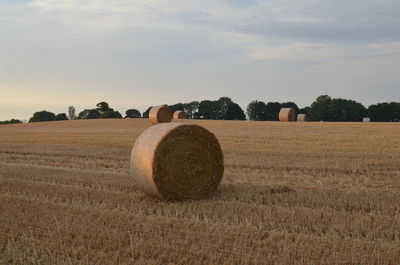 Hay bales on field against sky