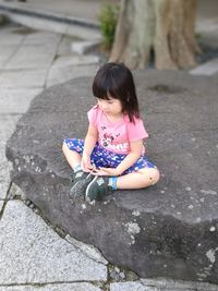 Cute girl sitting on stone wall