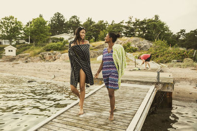 Mother and daughter communicating with each other while walking on jetty during vacation
