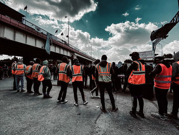 Rear view of people standing by bridge against sky